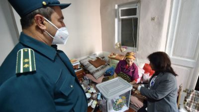 Пожилая женщина отдаёт свой бюллетень во время голосования на дому на выборах президента Узбекистана в Ташкенте 24 октября 2021 года. (Vyacheslav Oseledko/ AFP via Getty Images)
