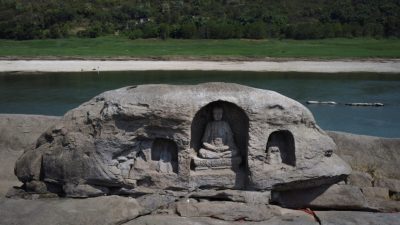 Некогда затопленная статуя Будды находится на вершине рифа острова Фойелян в реке Янцзы, который появился после падения уровня воды из-за региональной засухи в Чунцине, Китай, 20 августа 2022 года. (Thomas Peter/Reuters) 