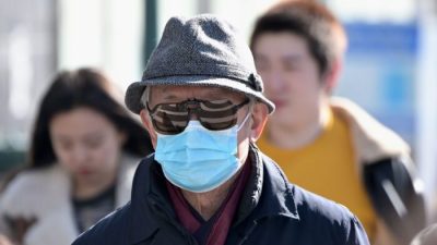 Мужчина надевает хирургическую маску во Флашинге в нью-йоркском округе Куинс, 3 февраля 2020 года. (Johannes Eisele/AFP via Getty Images)