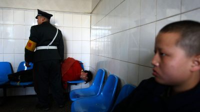 Мужчина, которого только что поместили в психиатрическую больницу Куньмина, лежит на стульях, Куньмин, провинция Юньнань, Китай, 1 декабря 2007 года. (China Photos/Getty Images)