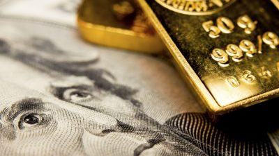 Крупный план 20-долларовой банкноты и золотых слитков. (Corlaffra/Shutterstock)

