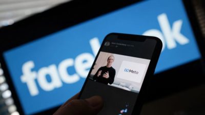 На фотографии на смартфоне генеральный директор Facebook Марк Цукерберг представляет логотип META. (Chris Delmas/AFP via Getty Images)