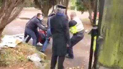 Скриншот из видео, на котором полицейский пытается спасти гонконгского протестующего, избитого у китайского консульства в Манчестере, Англия, 16 октября 2022 г. (Скриншот/Силы обороны коренных народов Гонконга через The Epoch Times)