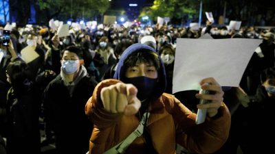 Люди держат белые листы бумаги в знак протеста в Пекине 27 ноября 2022 года. (Thomas Peter/Reuters)