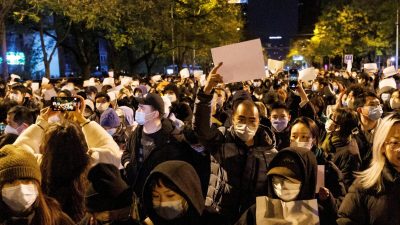 Люди держат белые листы бумаги в знак протеста против ограничений COVID-19 в Пекине, 27 ноября 2022 г. (Thomas Peter/Reuters) 