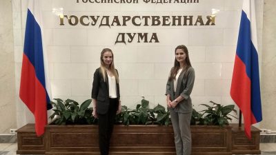 Две девушки стоят между российскими флагами в Государственной думе РФ. Фото: НС Интеграция/flickr.com/Public domain