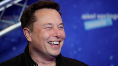 Владелец SpaceX и генеральный директор Tesla Илон Маск смеется, выходя на красную дорожку церемонии вручения премии Axel Springer Awards в Берлине, 1 декабря 2020 года. (Hannibal Hanschke/AFP via Getty Images)